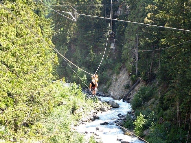 two people zip lining over Fitzsimmons Creek in Whistler in summer