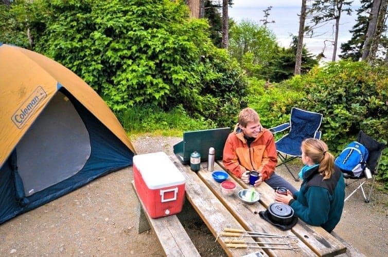 two people sitting at camp table with tent camping in bc