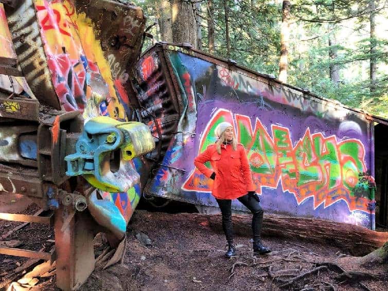 lady in orange coat in front graffiti covered train wreck in whistler
