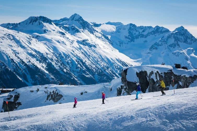 family skiing down whistler mountain in winter